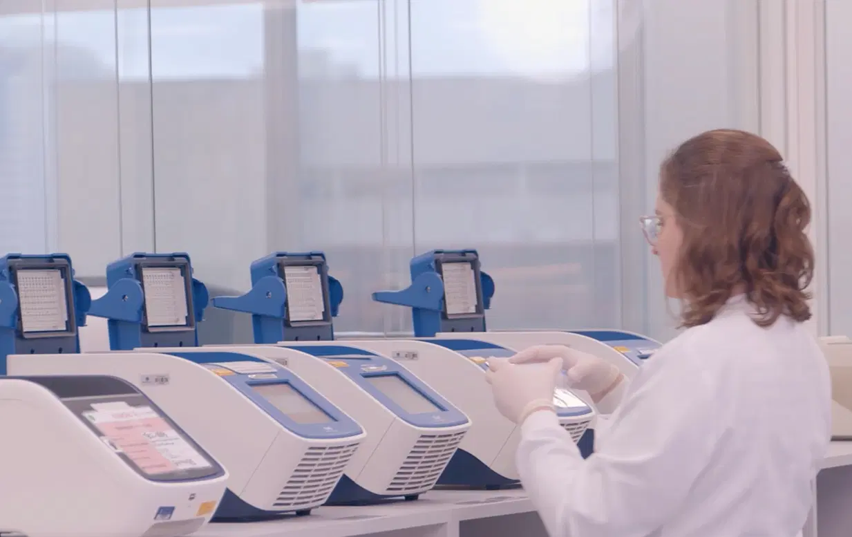 Pesquisadora operando termocicladores em laboratório de biotecnologia para análise de DNA